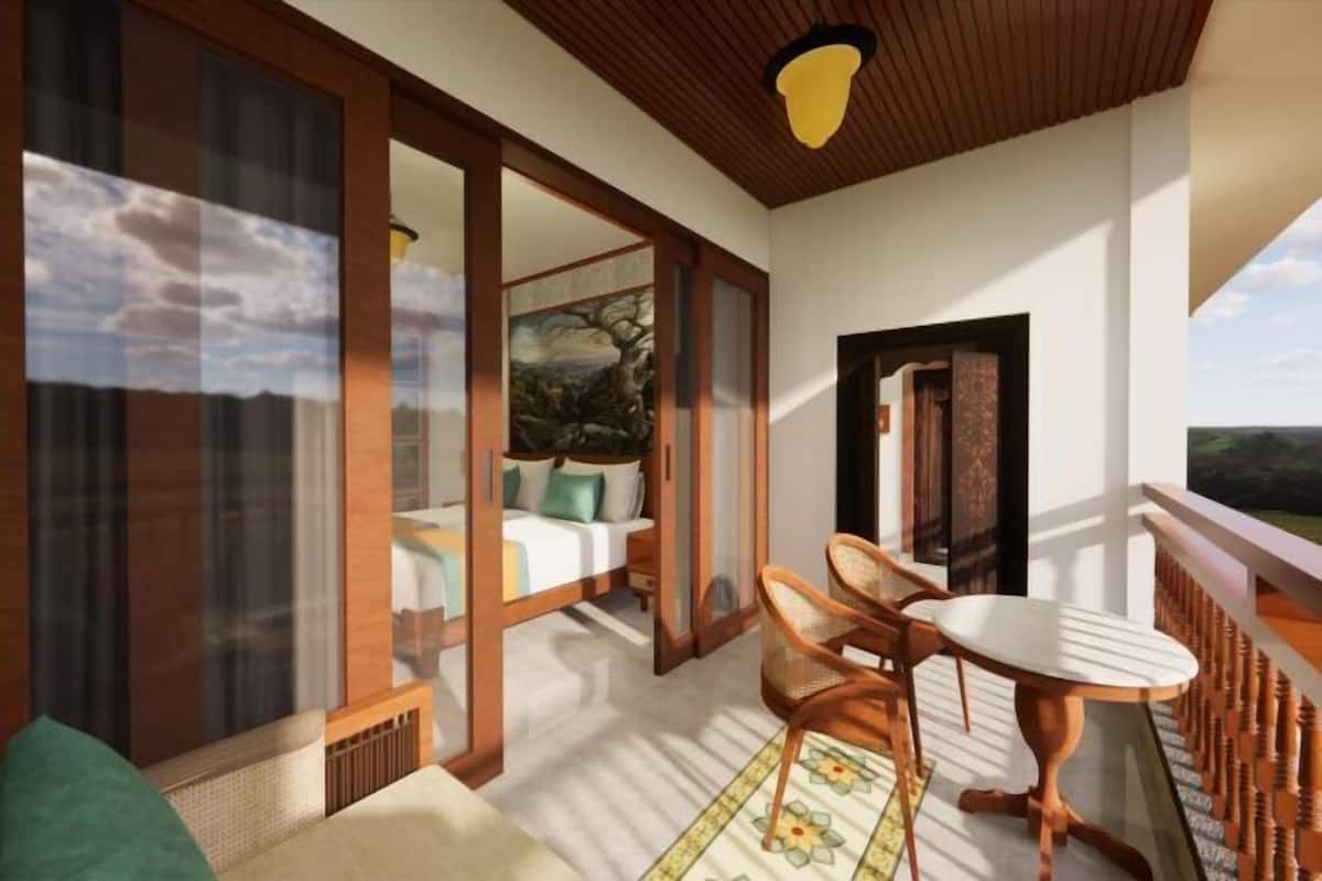 Une chambre avec un lit, une table à manger et des chaises, un balcon avec une balustrade et une grande fenêtre donnant sur un beau paysage.