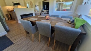 Un comedor con una mesa de madera, sillas tapizadas en gris y protectores de mesa tejidos.
