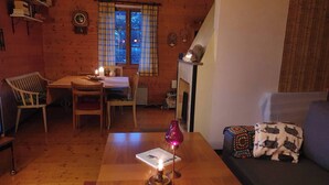 Un salon chaleureux avec une table en bois, un canapé, un coin repas avec des chaises et une fenêtre avec des rideaux.