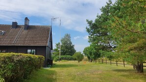 Une maison avec un toit en tuiles, une cheminée et un mât pour drapeau.