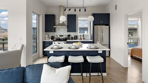A modern kitchen with a central island, bar stools, and a dining area with a sofa and chairs. - Luxury 2Bd Condo DT Minneapolis, Minutes From Convention Center & US Bank Arena (Minneapolis)
