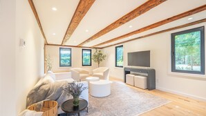 A modern living room with wooden beams, a large TV, and a sofa.