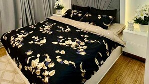 Une chambre moderne avec un grand lit, un ventilateur de plafond et un luminaire fixé au mur.