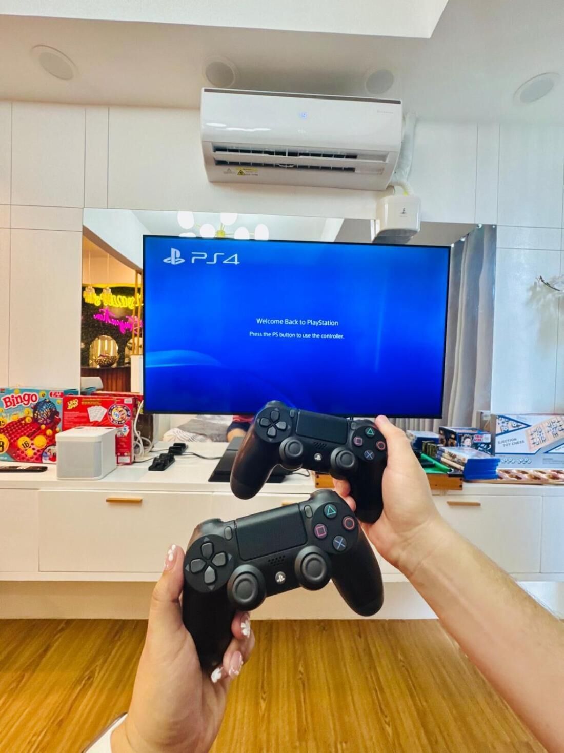 Une pièce équipée d’une console PlayStation 4, de deux manettes de jeu et d’un téléviseur affichant le logo PlayStation.