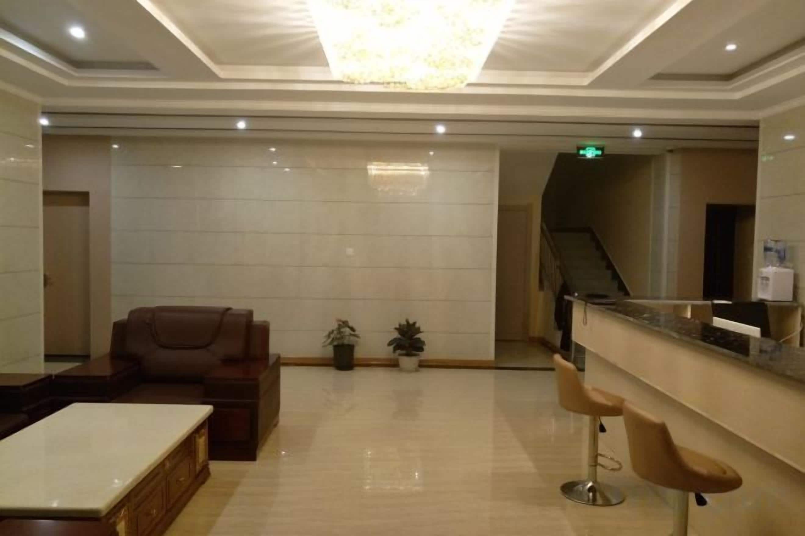 Un vestíbulo de hotel con una recepción, zona de estar y una escalera.
