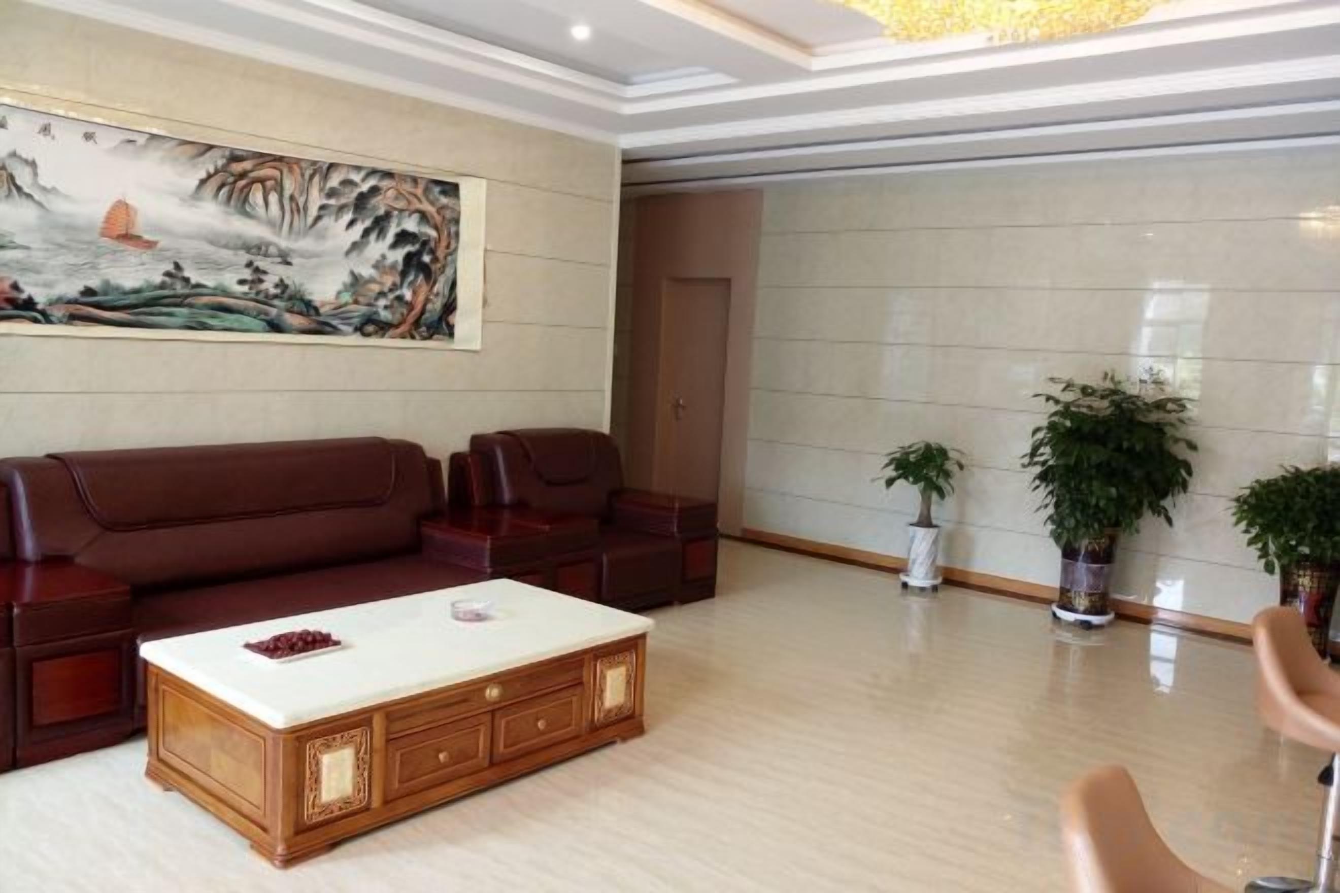 A spacious living room with a large sofa set, a coffee table, and two potted plants.