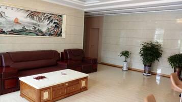 A spacious living room with a large sofa set, a coffee table, and two potted plants.