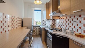 A modern kitchen with a wooden countertop, stainless steel appliances, and patterned tile backsplash.