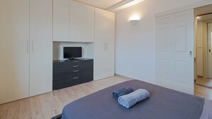 A bedroom with a bed, a television on a dresser, and a door.