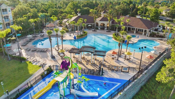 A resort with multiple swimming pools, a water park, and lounge areas surrounded by palm trees. - Disney Retreat w/ Wizard & Galaxy Rooms (Kissimmee)
