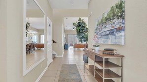A hallway with a dining area, a large plant, and a painting on the wall. - Disney Retreat w/ Wizard & Galaxy Rooms (Kissimmee)