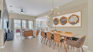 A spacious dining area with a large table and chairs, a ceiling fan, and hexagonal mirrors on the wall. - Disney Retreat w/ Wizard & Galaxy Rooms (Kissimmee)