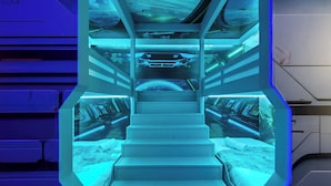 En futuristisk hotellinteriör med en central trappa, flera våningsplan och en högteknologisk kontrollpanel.