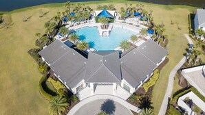 Vue aérienne d’un complexe hôtelier doté d’une piscine centrale, entouré de palmiers et bordé par une étendue d’eau.