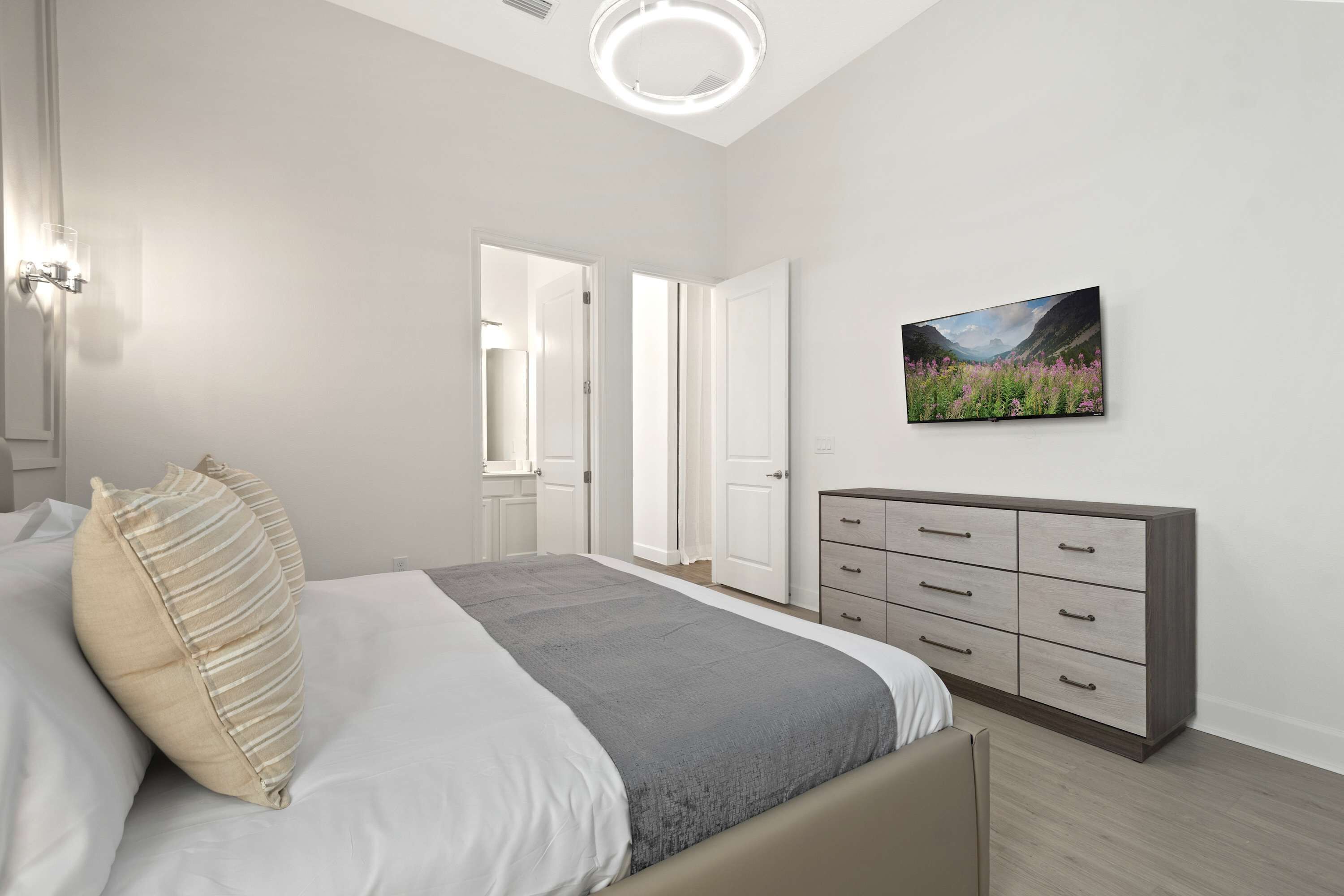 A modern bedroom with a bed, a dresser, and a painting on the wall.