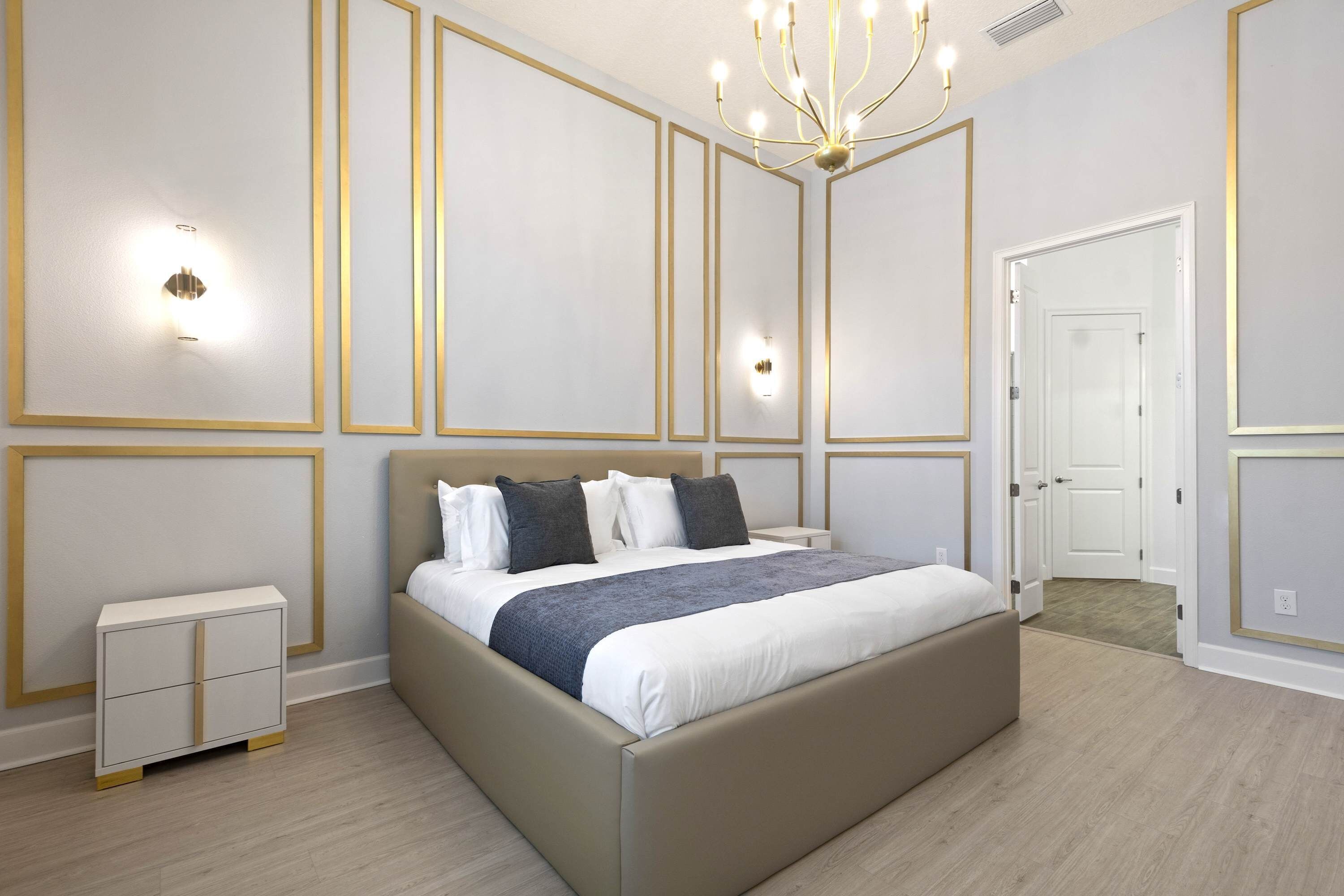 A modern bedroom with a large bed, bedside tables, and a chandelier.