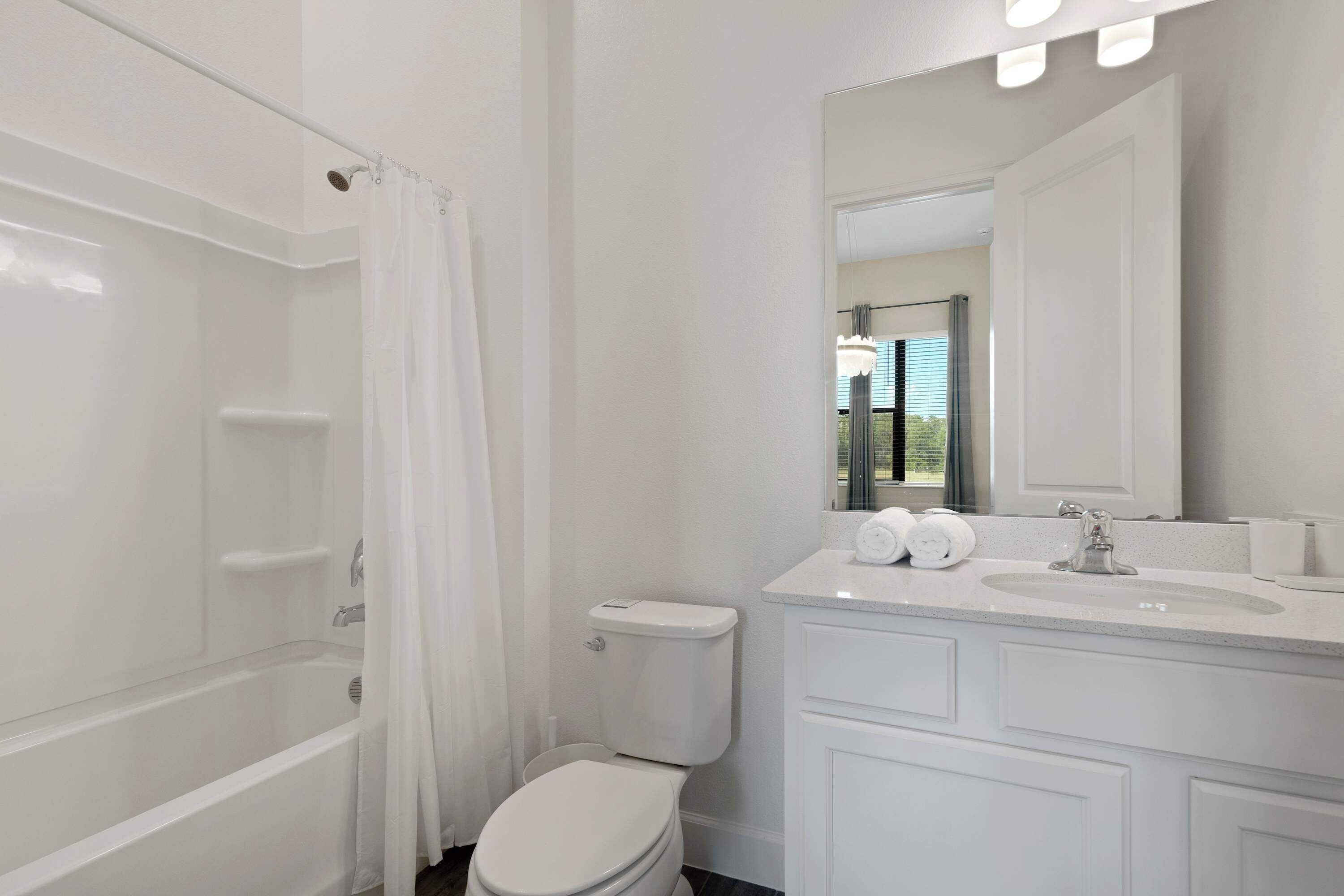 A modern bathroom with a bathtub, toilet, and vanity with a mirror.