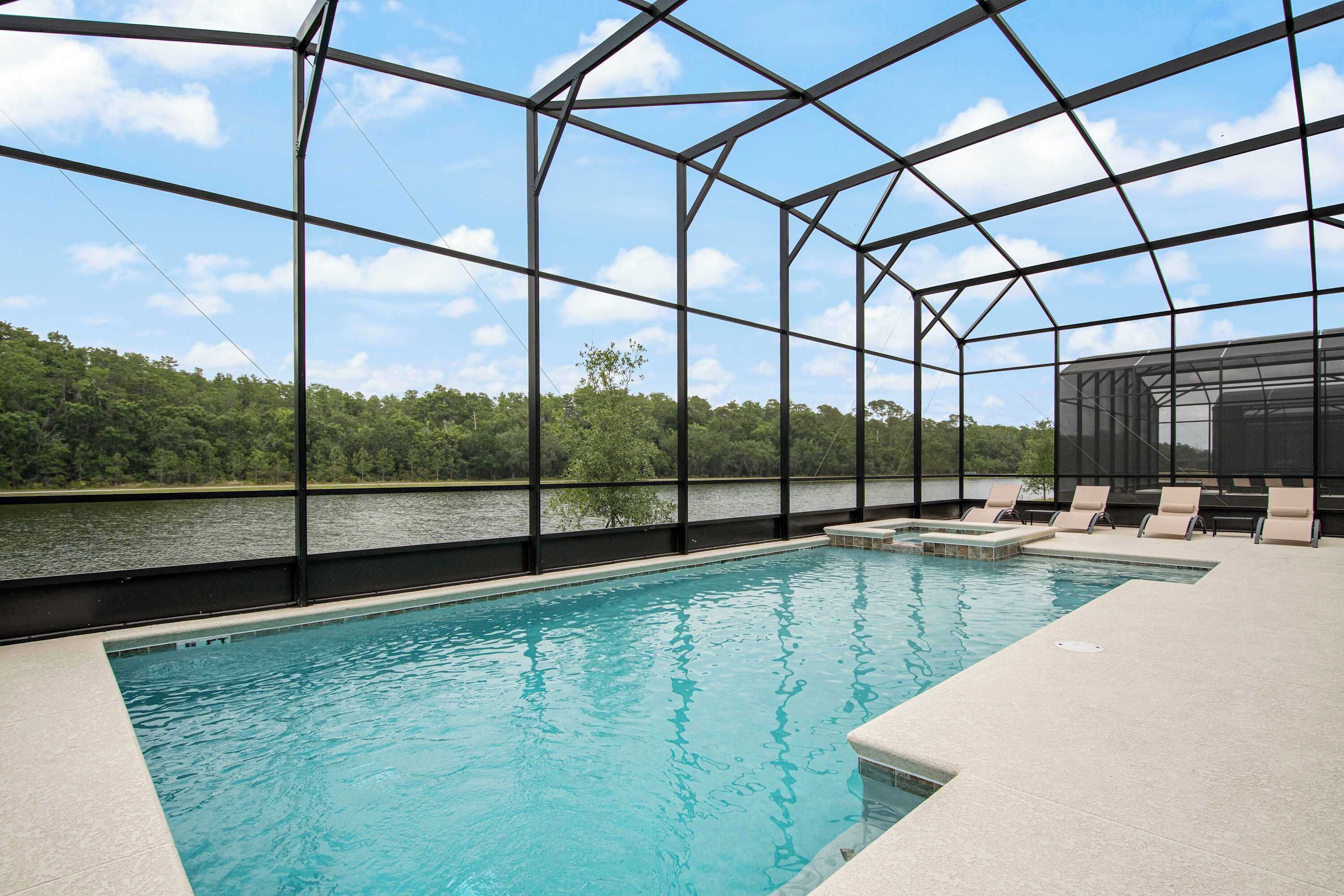 A swimming pool with a clear view of the surrounding landscape, including a body of water and trees.