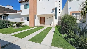 A modern two-story house with a well-maintained lawn, a wooden front door, and a garage. - Casa Maru (Tequisquiapan)