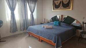 A bedroom with a bed, curtains, a bedside table, a chair, and a wall-mounted artwork. - Casa Maru (Tequisquiapan)