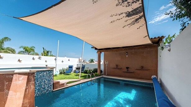A swimming pool with a sunshade, a small waterfall feature, and a few lounge chairs. - Casa Maru (Tequisquiapan)