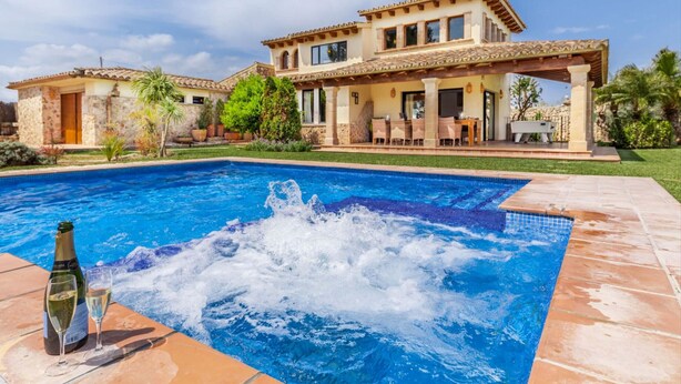 Ett stort hus med en swimmingpool, ett bubbelbad och utemöbler.