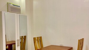 Uma área de refeições com uma mesa e cadeiras de madeira, um armário branco com portas de vidro e um ar-condicionado instalado no teto.
