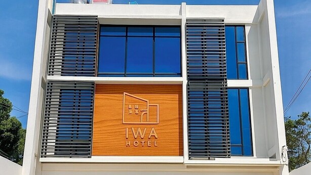 Um hotel moderno com um logotipo destacado, grandes janelas e um telhado plano.