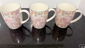 Drie glazen mokken met bloemenmotieven op een reflecterend oppervlak.