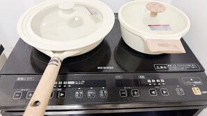 Een IRIS OHYAMA elektrische kookplaat met twee pannen en een steelpan.