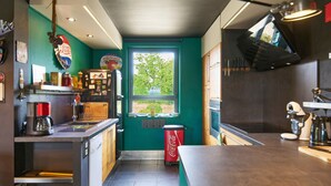 Una cocina compacta con ventana, un refrigerador rojo de Coca-Cola y diversos electrodomésticos.