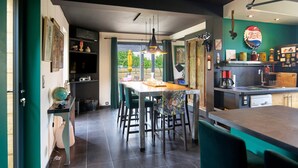 Una cocina moderna con comedor, que incluye una isla grande, iluminación colgante y vistas a través del ventanal.