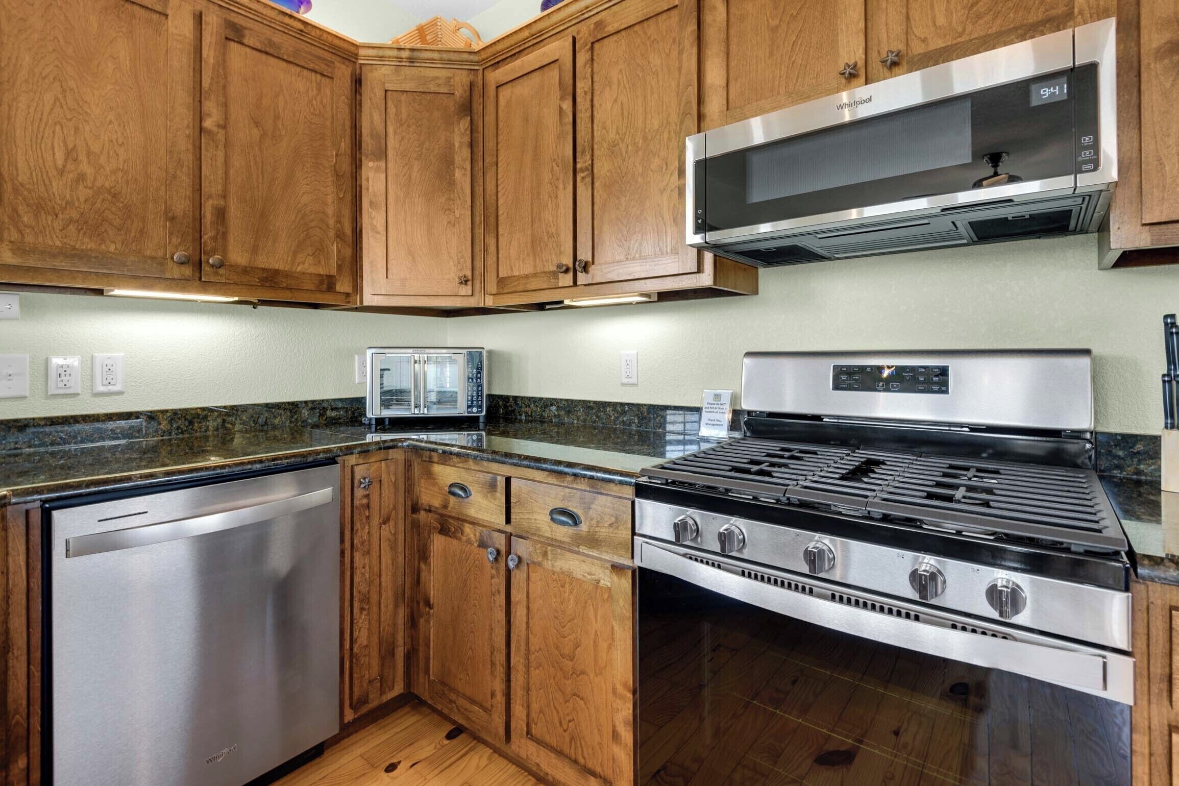 A kitchen with wooden cabinets, a stainless steel dishwasher, a built-in microwave, and a gas stove.
