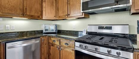 A kitchen with wooden cabinets, a stainless steel dishwasher, a built-in microwave, and a gas stove.