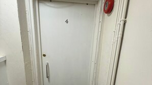 A white door with a number '4' on it, a door handle, and a red fire alarm on the wall.