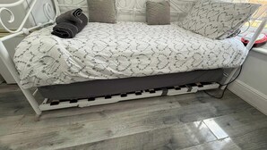 A bed with a patterned bedspread, pillows, and a rolled towel.