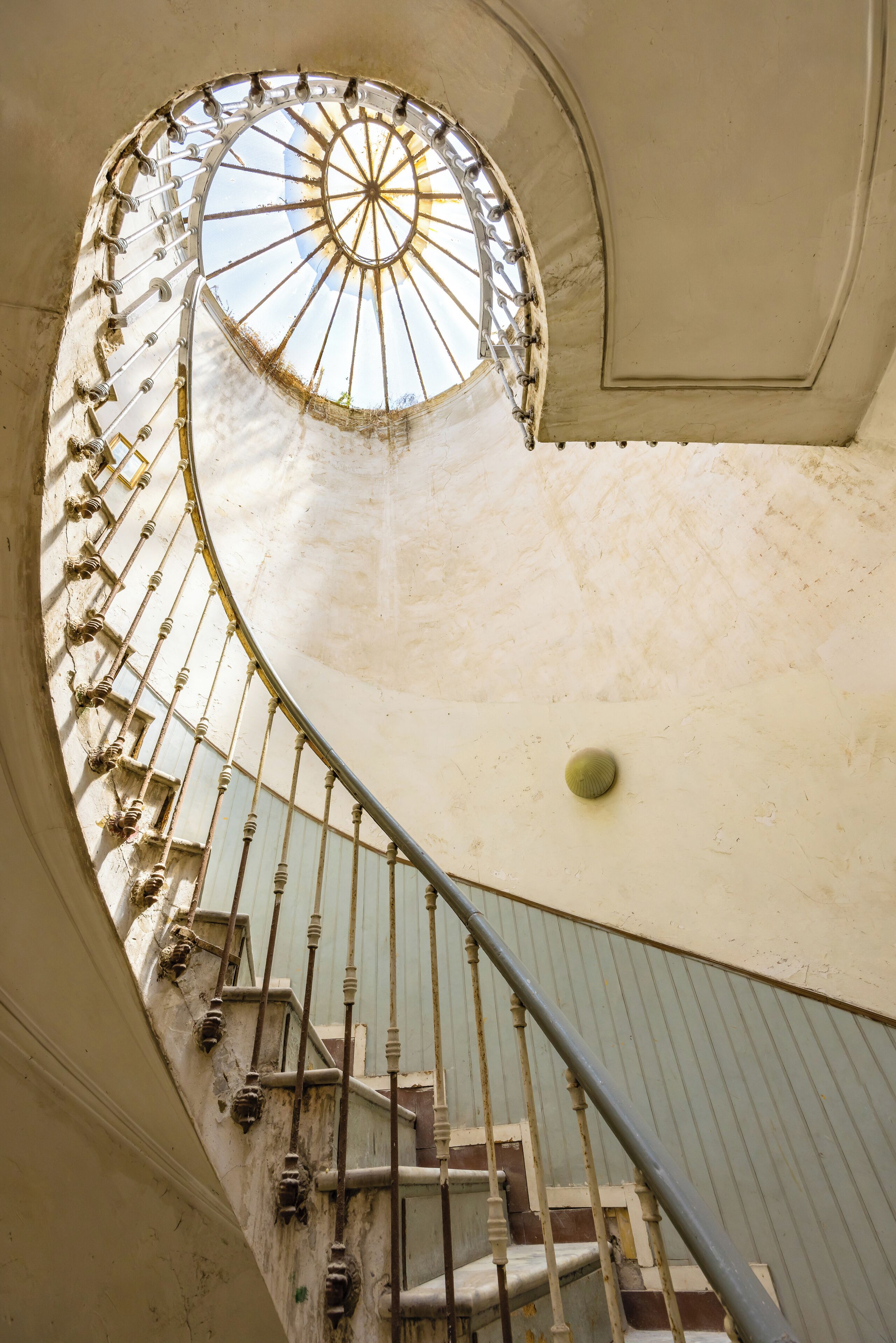 Un escalier en colimaçon surmonté d’une coupole de verre, menant à l’étage supérieur.