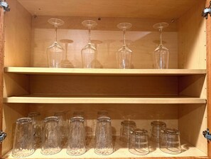 A wooden cabinet with two shelves, each holding multiple wine glasses and clear glass jars. - Chicago 1BR Near Lake Michigan & Pratt Beach – Free Parking (Chicago)