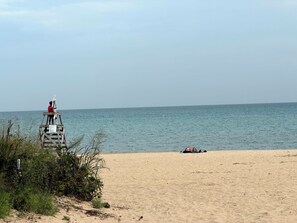 A beach with a lifeguard tower and a person lying on the sand. - Chicago 1BR Near Lake Michigan & Pratt Beach – Free Parking (Chicago)