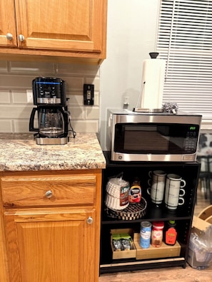 A kitchen with wooden cabinets, a coffee maker, a microwave, and shelves with kitchen items. - Chicago 1BR Near Lake Michigan & Pratt Beach – Free Parking (Chicago)