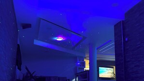 A modern interior with a reflective floor, a ceiling with a recessed light, and a television screen displaying a beach scene.