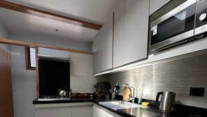 Une cuisine moderne avec des meubles gris, un plan de travail noir et un four à micro-ondes encastré.
