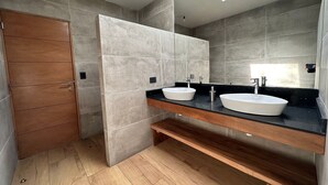 Une salle de bain moderne avec deux vasques, un meuble-lavabo en bois et une lucarne.
