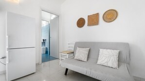 A modern living room with a white sofa, a white chair, and a white refrigerator. There are three woven wall hangings above the sofa. - Holiday Home 'Istella - A' with Private Terrace (Sant'Anna Arresi)