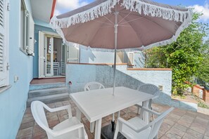 A patio with a table and chairs, an umbrella, and a door leading to an interior space.