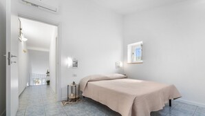 A bedroom with a bed, a small bedside table, a window, and a door leading to a hallway. - Holiday Home 'Istella - A' with Private Terrace (Sant'Anna Arresi)