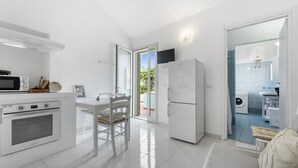 A modern kitchen with white appliances, a dining area with a table and chairs, and a view of the outside. - Holiday Home 'Istella - A' with Private Terrace (Sant'Anna Arresi)