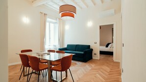 A modern living room with a glass dining table, orange chairs, and a teal sofa. - Casa Mia Navona (Rome)