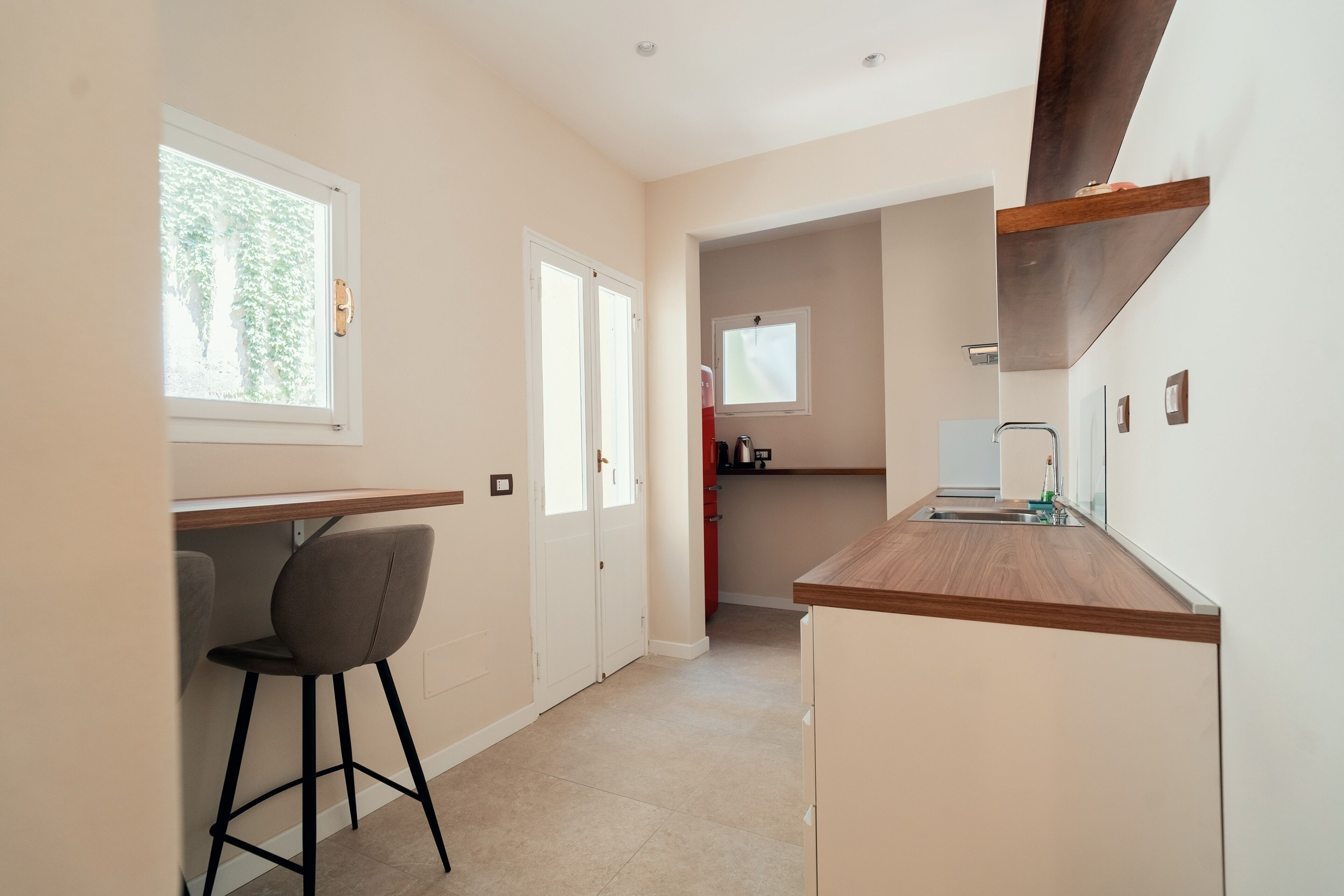 A modern kitchen with a wooden countertop, a built-in sink, and a small window.