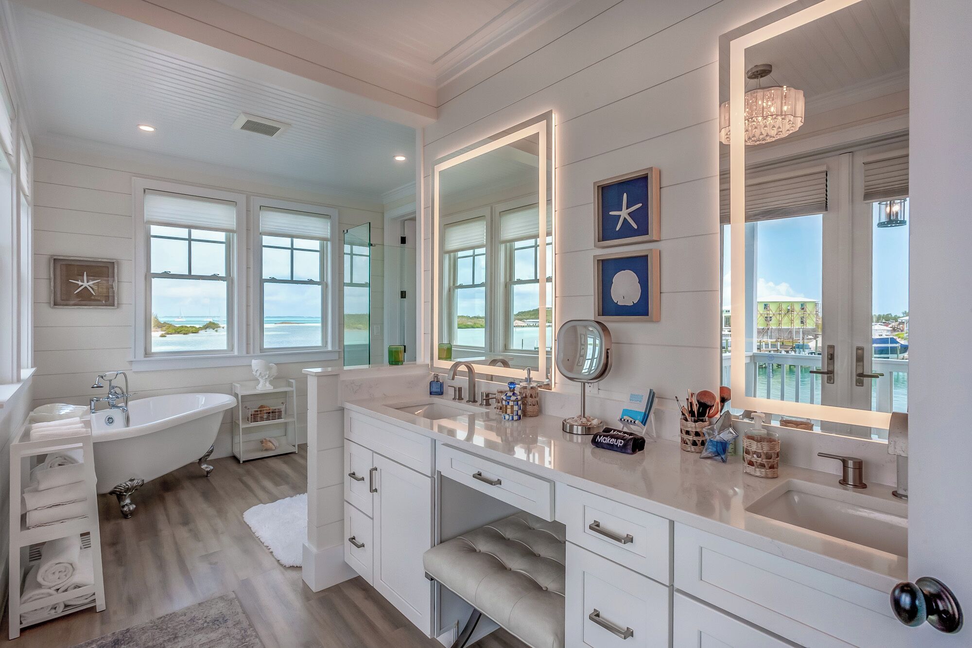 A spacious bathroom with a large bathtub, two sinks, and a vanity with storage drawers.